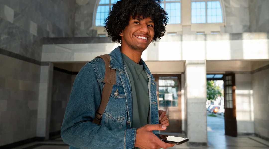 Một thanh niên tóc xoăn cầm điện thoại di động, biểu thị thông tin về giờ làm việc của sinh viên quốc tế tại Canada.