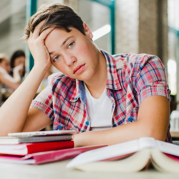  A young man sits at a table with books and a notebook, preparing to apply for a Canadian student visa.