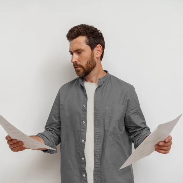 Man reviewing eligibility requirements for a Canada work permit while holding papers in his hands.