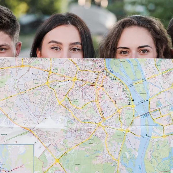 Three young people studying a map together, likely discussing their guide work permit options in Canada.