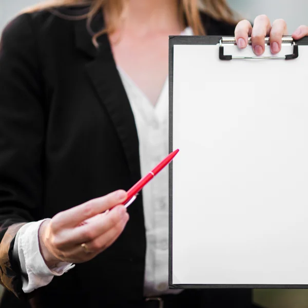 A woman holding a clipboard and a red pen, preparing to obtain a work permit for Canada.