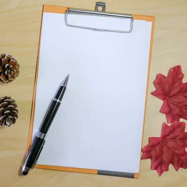 Autumn-themed background featuring a clipboard, pen, and colorful leaves, related to a guide for work permits in Canada.