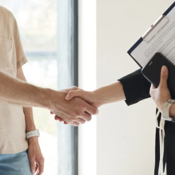 A man and woman shake hands in front of a clipboard, symbolizing collaboration for the Best Canadian Cities initiative.