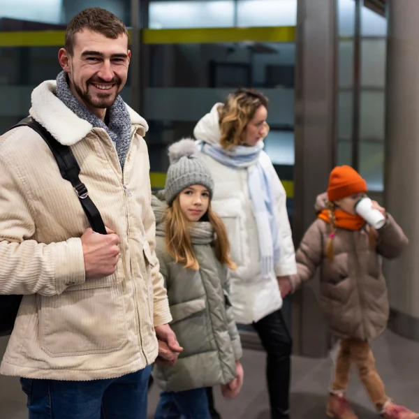 A man and two children descend an escalator, symbolizing family movement in the context of Canada's 2026 immigration plan.