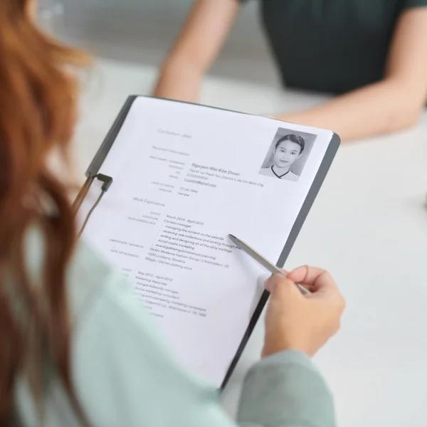 Người phụ nữ cầm hồ sơ xin việc và ghi chú trên đó, thể hiện sự chuẩn bị cho cơ hội việc làm.