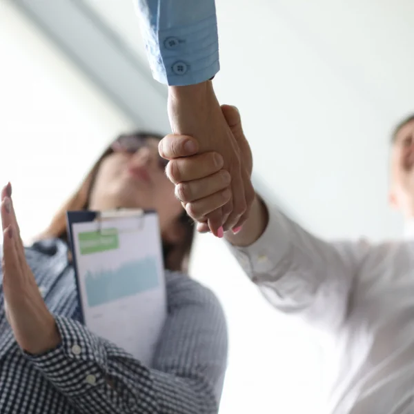 Two people shaking hands in an office, symbolizing a partnership focused on safety and sustainability for permanent residents.