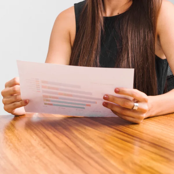 A woman sitting at a table holds a piece of paper, indicating her status as a Permanent Resident in Canada.