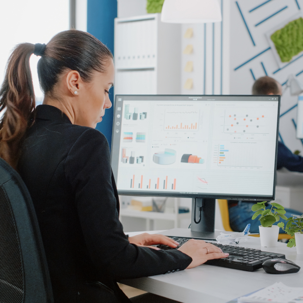 A woman is focused on her computer while working in a modern office environment.