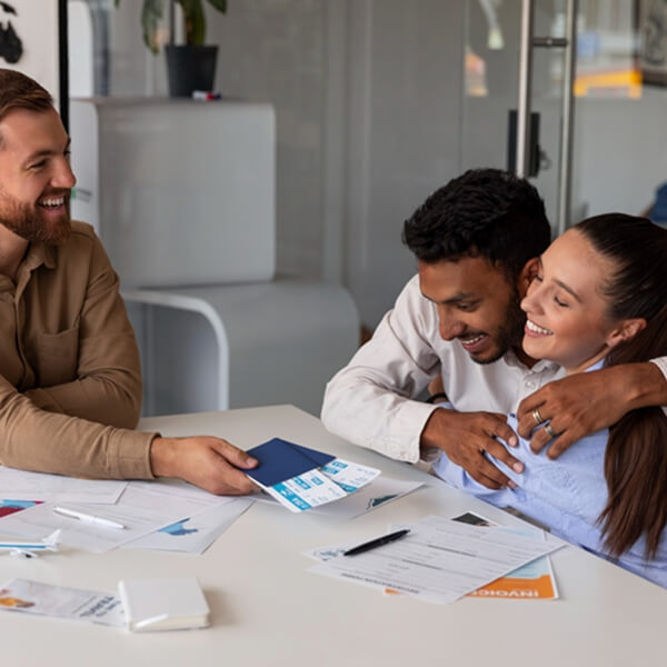 Ba người ngồi quanh bàn với giấy tờ, một người đàn ông ôm một người phụ nữ.